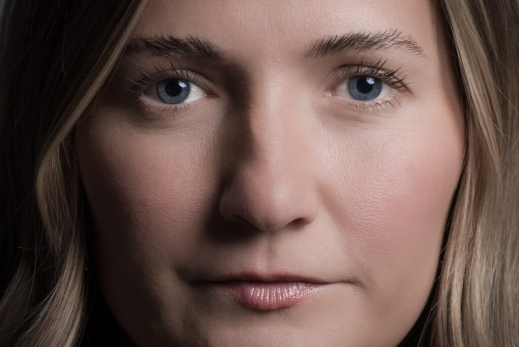 Expressive RAW studio soft color close-up portrait of a woman with a thoughtful, natural expression.