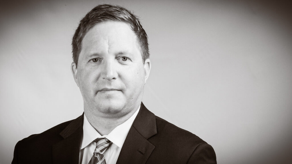 Executive black and white portrait with grey background and tight head and shoulders crop